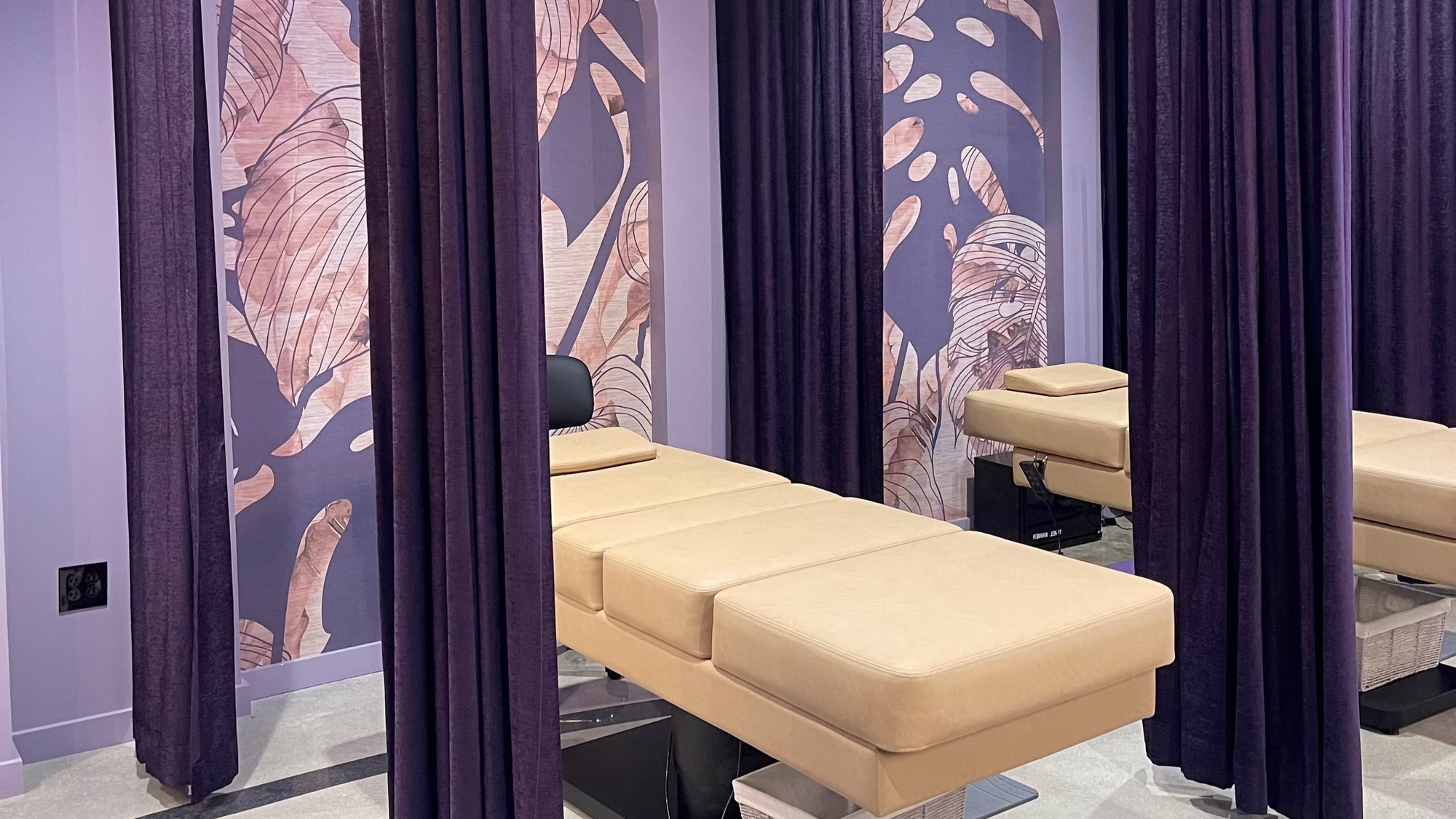 Beige massage table in a room with purple curtains and wall art