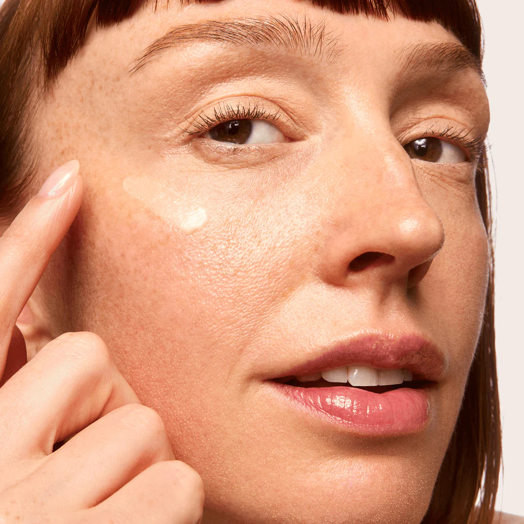 Close-up of a woman applying skincare product to her face.